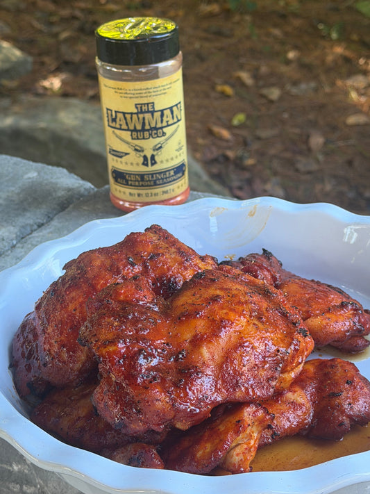 Grilled chicken thighs seasoned with The Lawman Rub Co. Gun Slinger All Purpose BBQ Seasoning, served in a white dish outdoors in Maryville, Tennessee.